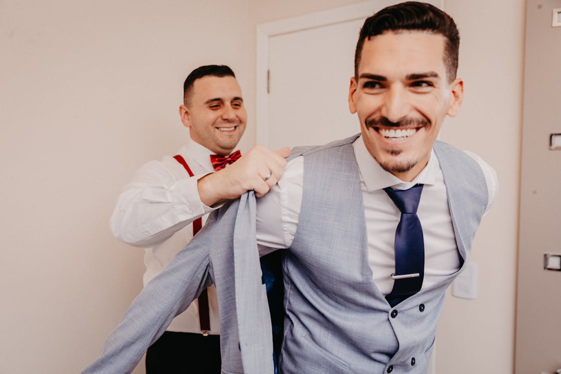 Man Helping Another Man Put On a Formal Jacket · Free Stock Photo