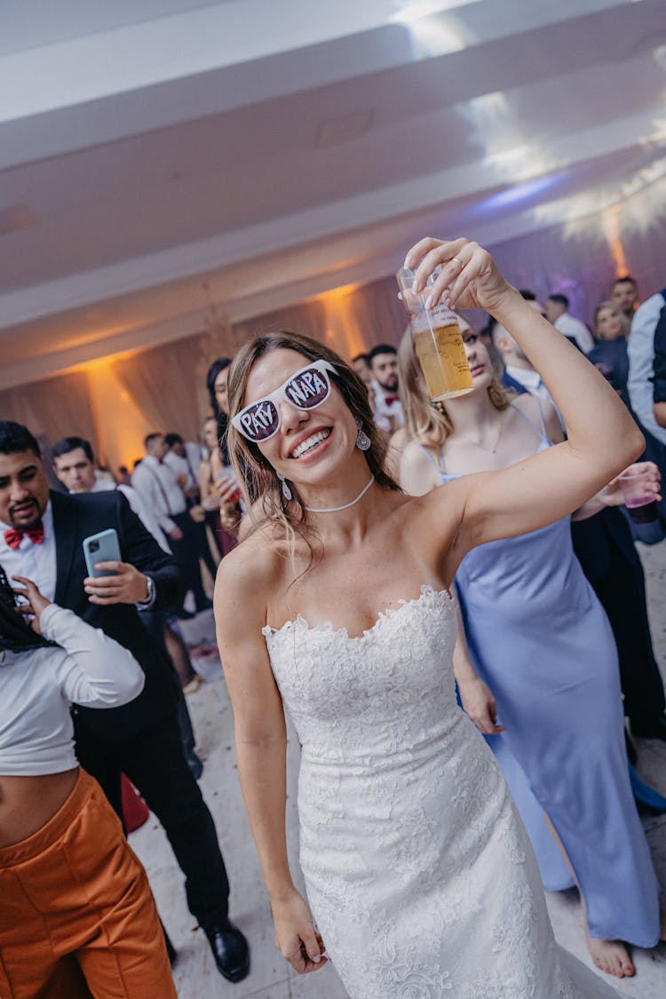 A Bride Holding A Drink During A Party