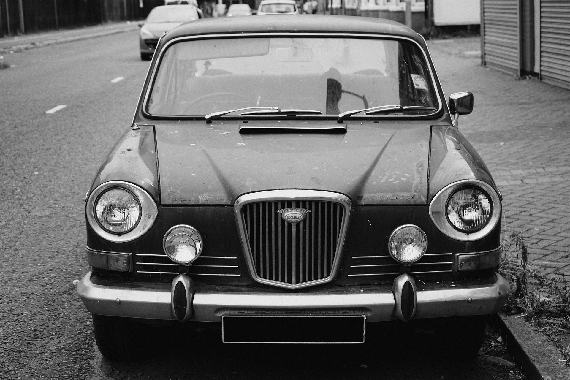 Classic black and white photo of a parked vintage Wolseley car on a Liverpool street.