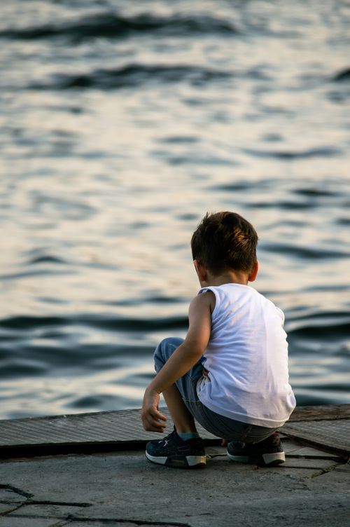 Free A child sits pensively by the Bosphorus in Istanbul, enjoying the waterfront view. Stock Photo
