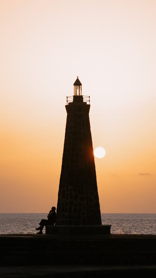 Free Silhouette of Lighthouse by the Sea  Stock Photo
