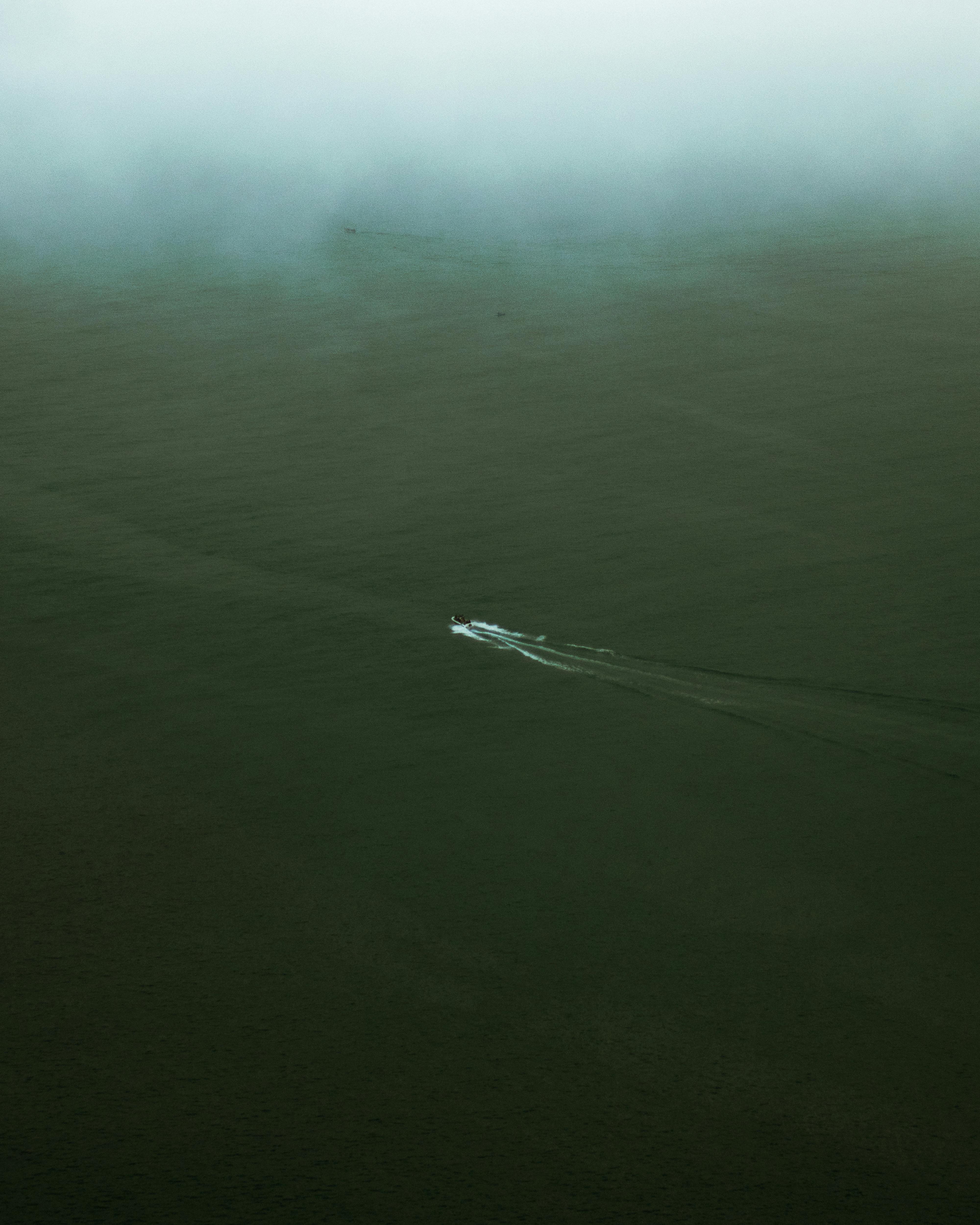 Aerial view of a speedboat navigating the calm, fog-covered sea in Ténès, Algeria.