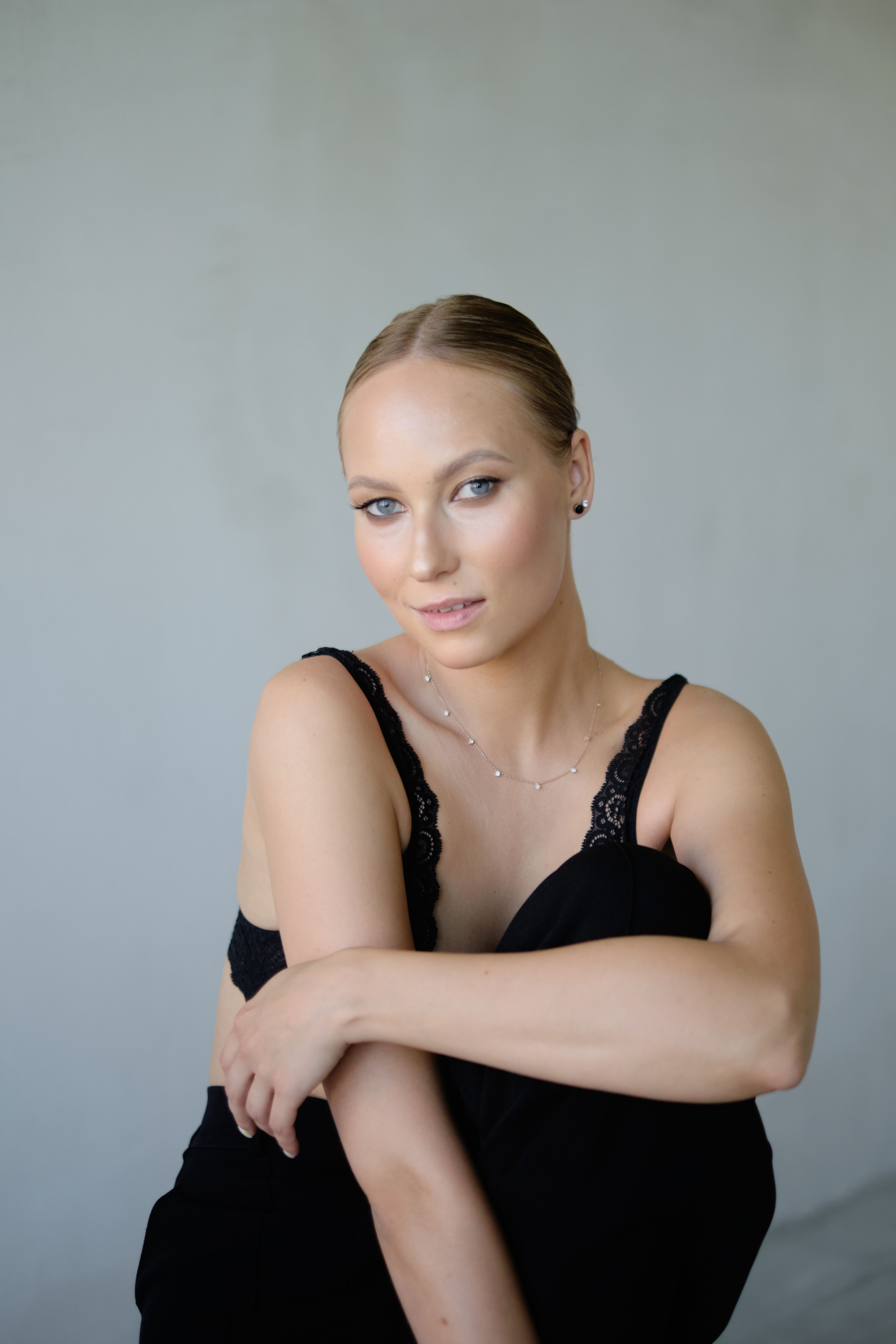 Stylish portrait of a woman in black attire against a gray backdrop.