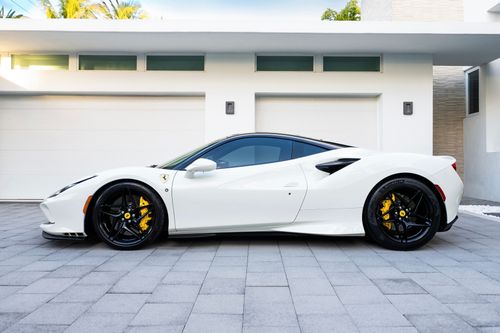 Free Sleek white sports car with black rims and yellow calipers parked outside a modern home. Stock Photo