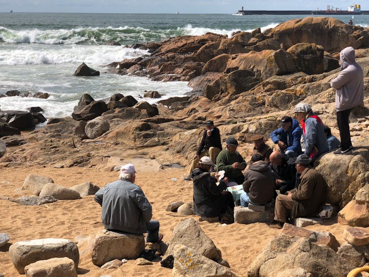 Group Of People Sitting On A Rocky Beach 