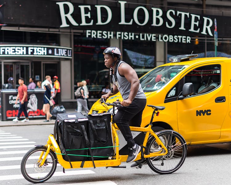 Man Driving A Yellow Cargo Bike In The City Street