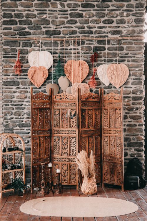 Free Cozy rustic interior featuring a wooden divider with heart decorations and stone wall background. Stock Photo