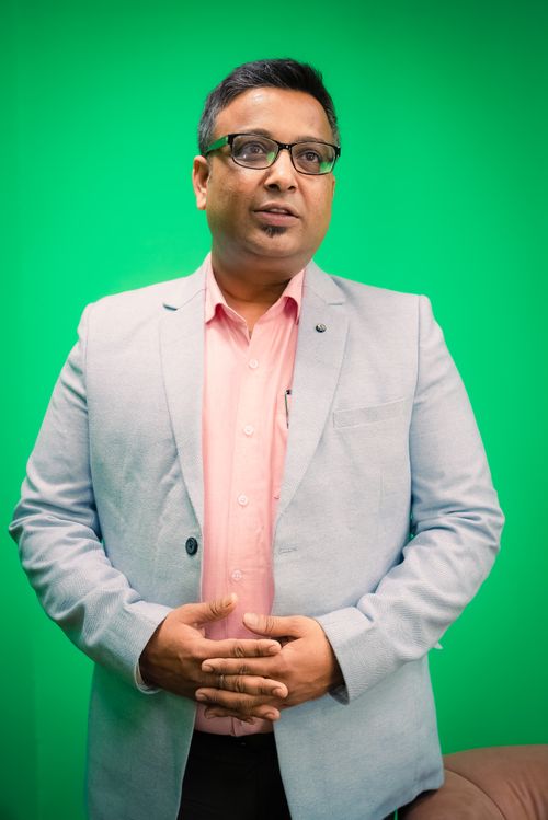 Free Portrait of a South Asian businessman in a light blazer against a green background. Stock Photo