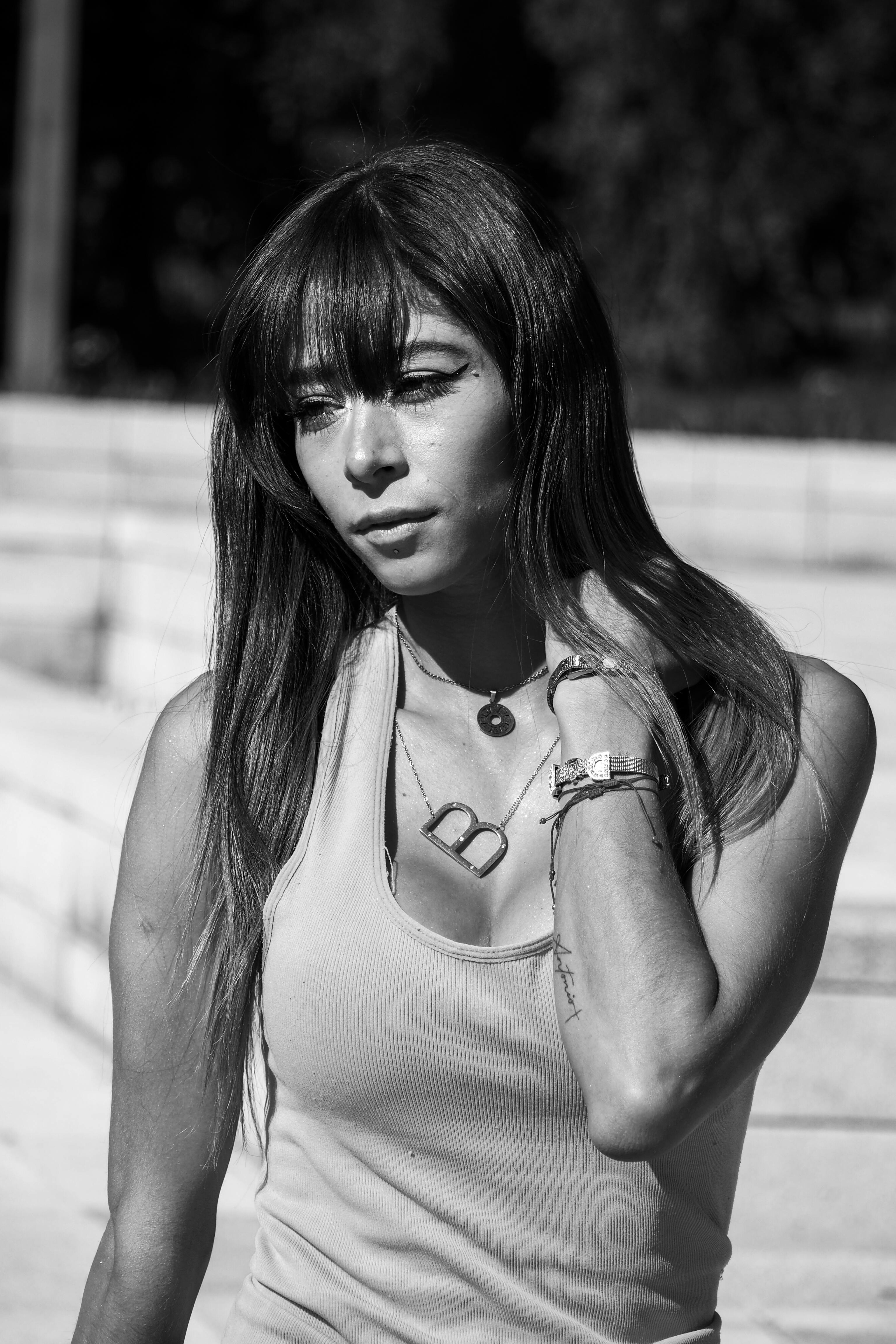 grayscale-photo-of-woman-in-tank-top-and-pants-with-hands-behind-her