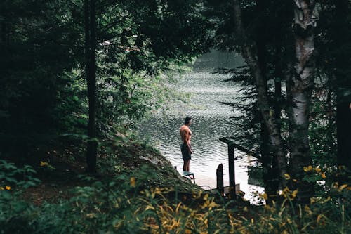 A Topless Man Standing Beside the Lake