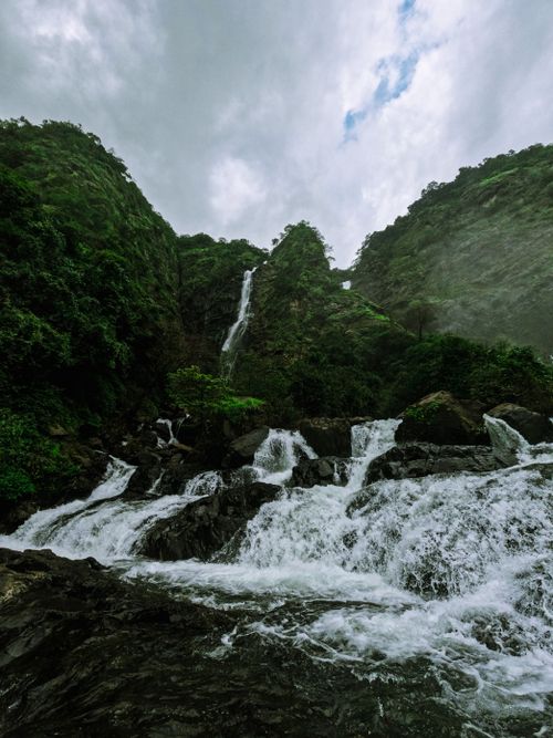 Free Stunning waterfall cascading down mountains in Virdi, India. Lush greenery complements the flowing water. Stock Photo