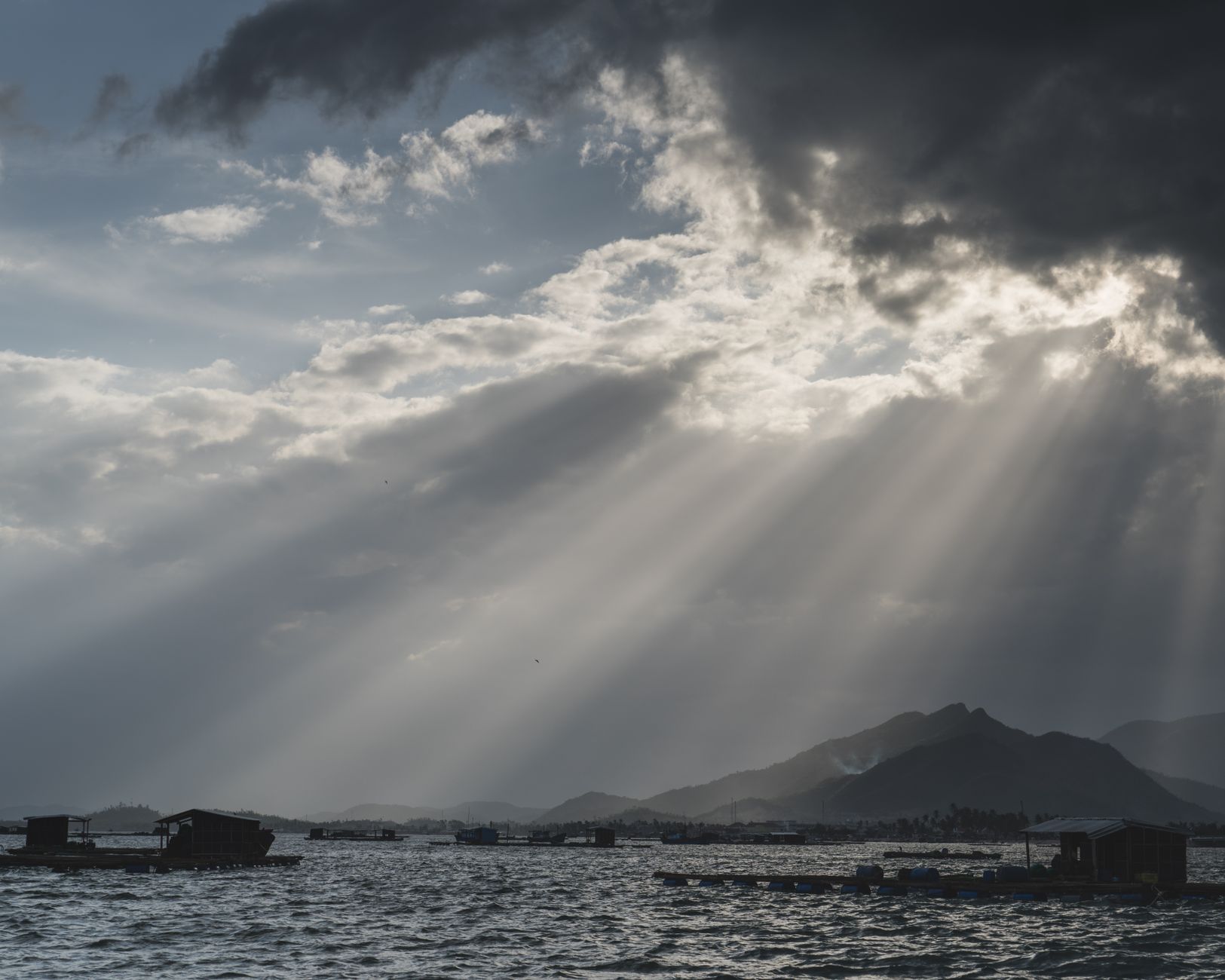 Dramatic sunbeams break through clouds over Phan Thiet coast. A tranquil seascape showcasing nature's beauty.