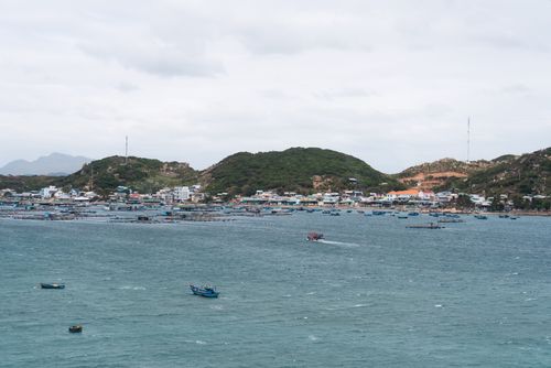 Free Aerial view of Phan Thiet's vibrant coastline with boats and hills, offering a serene landscape. Stock Photo