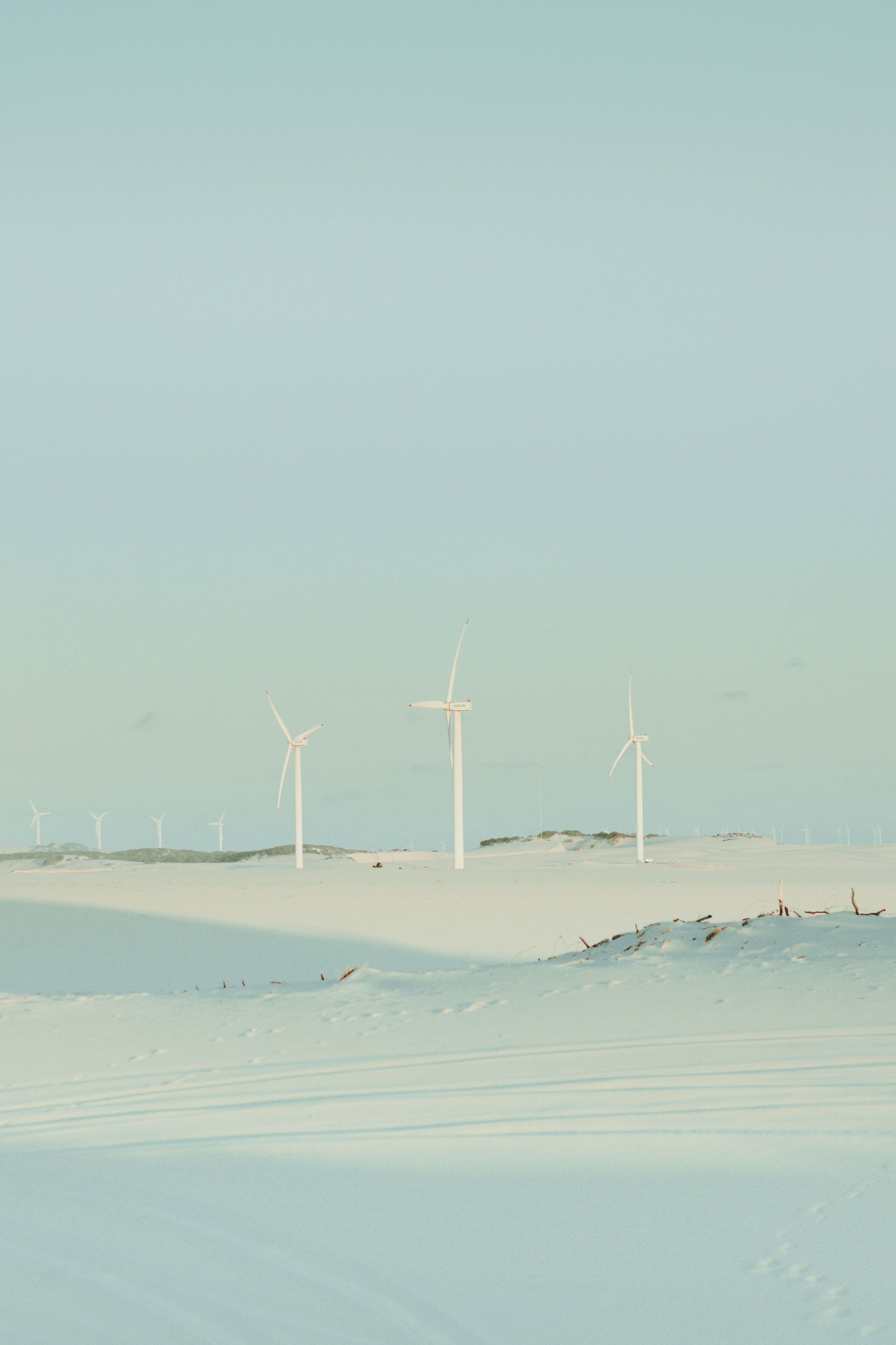 Peaceful wind turbines on the sand dunes of Cumbe, Brazil, under a clear sky.