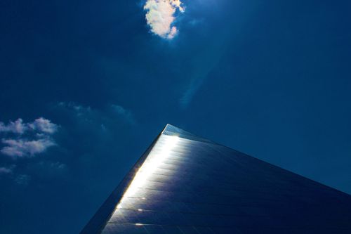Free Striking low-angle shot of a modern pyramid structure reflecting sunlight under a deep blue sky. Stock Photo