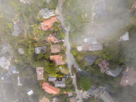 Aerial view of a suburban neighborhood with mist partially covering the houses and roads.