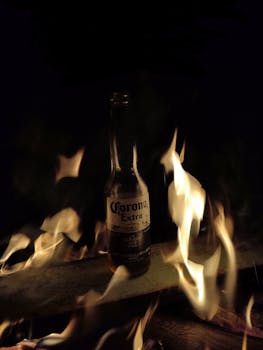 A dramatic shot of a Corona beer bottle amid swirling flames creates a striking visual.