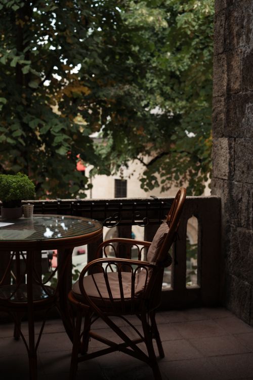 Free A serene balcony in Bursa featuring a rattan chair and green foliage set against a stone wall. Stock Photo