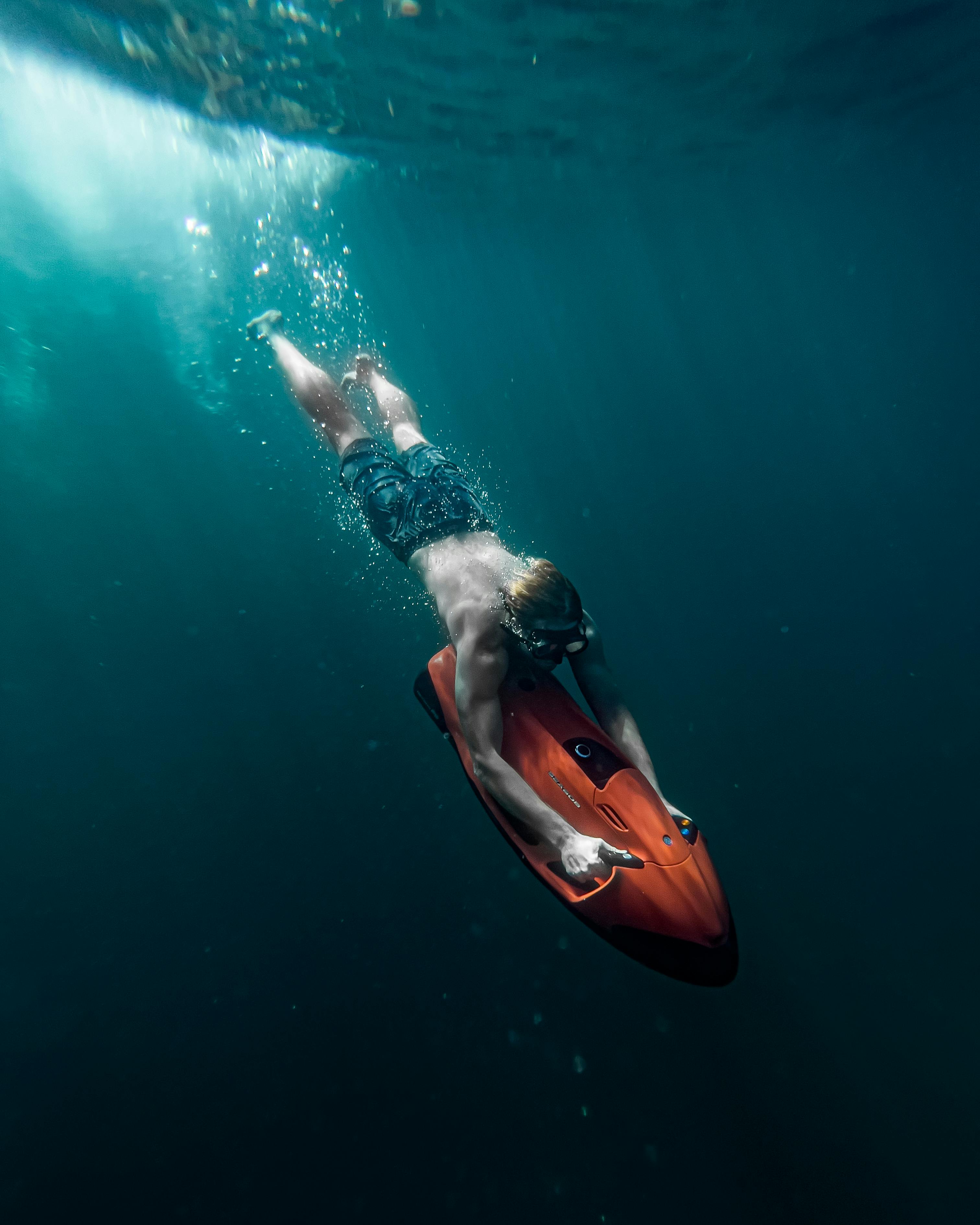 man freediving in sea with underwater scooter