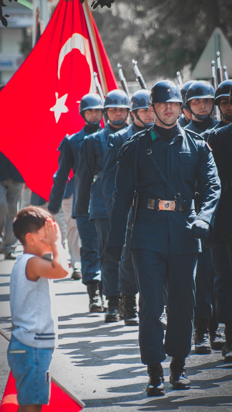 Little Boy Saluting A Group Of Marching Soldiers