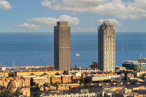 Free Aerial view of Barcelona's skyline featuring iconic skyscrapers and the Mediterranean Sea. Stock Photo