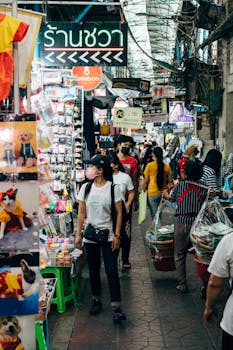 Vibrant street market in Thailand with diverse shoppers exploring stalls. Captures lively atmosphere.