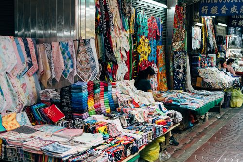 Free A vibrant display of colorful fabrics in an urban market stall, showcasing variety and abundance. Stock Photo