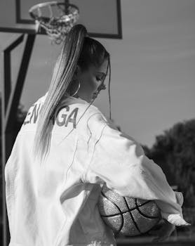 Stylish black and white portrait of woman holding a basketball outdoors.