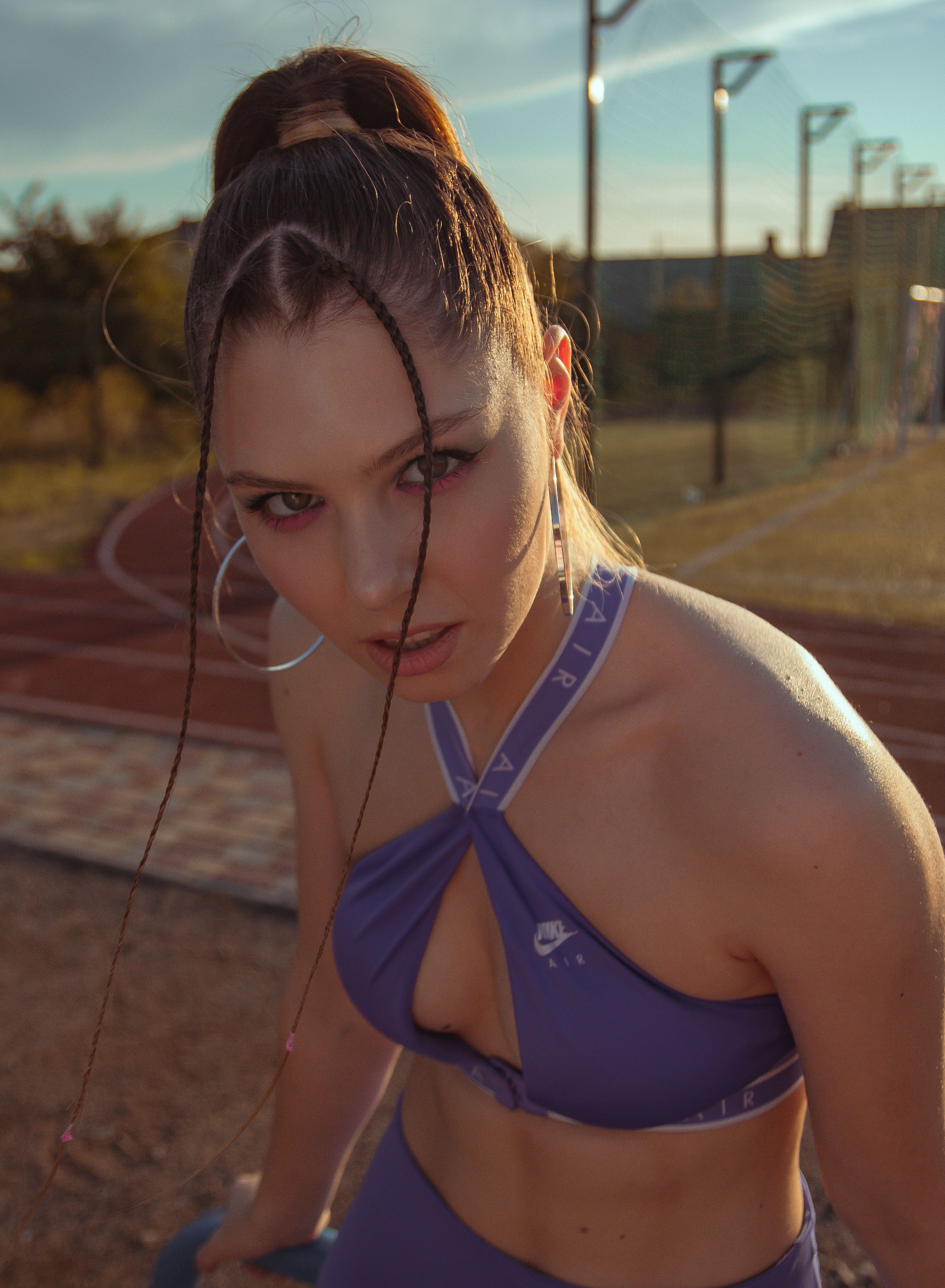 Young woman in stylish bikini posing outdoors on a sunny track field.