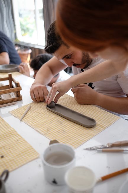 Participants engaged in a hands-on ceramic craft session indoors, focusing on a clay art project.
