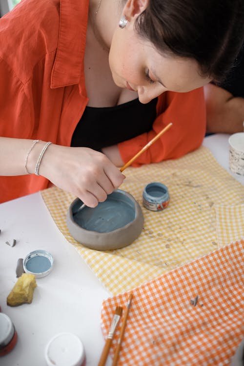 Young Woman Painting a Bowl with a Paintbrush