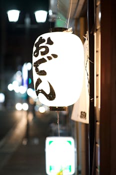 Glowing paper lantern with Japanese calligraphy lighting up a street in Takasaki, Japan.