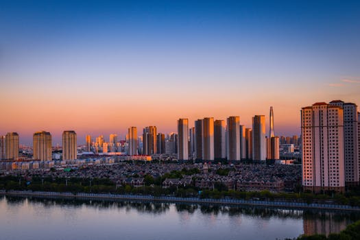 A stunning urban skyline showcasing skyscrapers by the river during sunset.