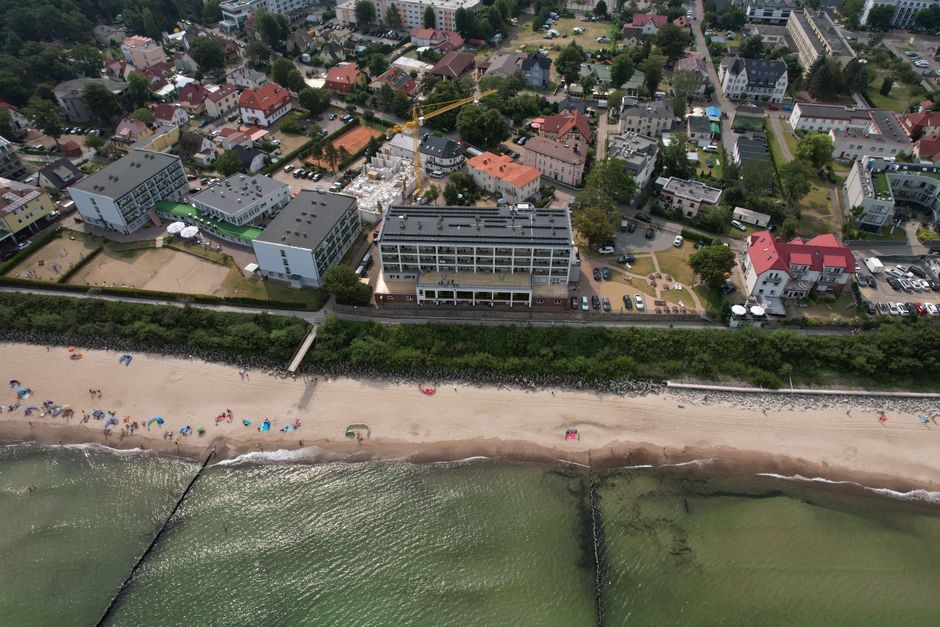Aerial view of a coastal town with beachfront and buildings on a sunny day.