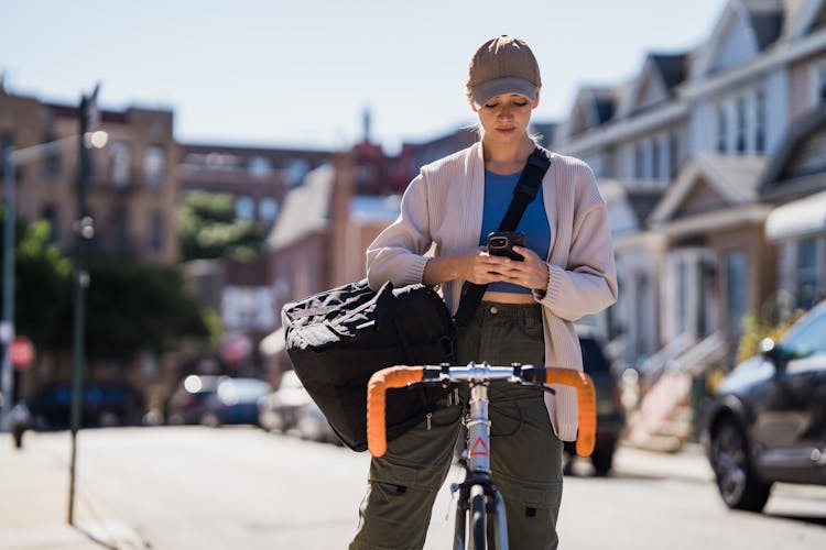 Woman Biker With Big Shoulder Bag Texting Message On Cellphone