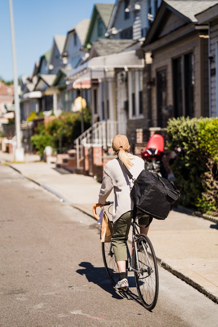 Delivery Woman Riding Bike In Street And Looking For Address