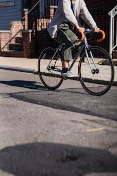 A woman rides a bicycle on a suburban street, capturing urban leisure and style.