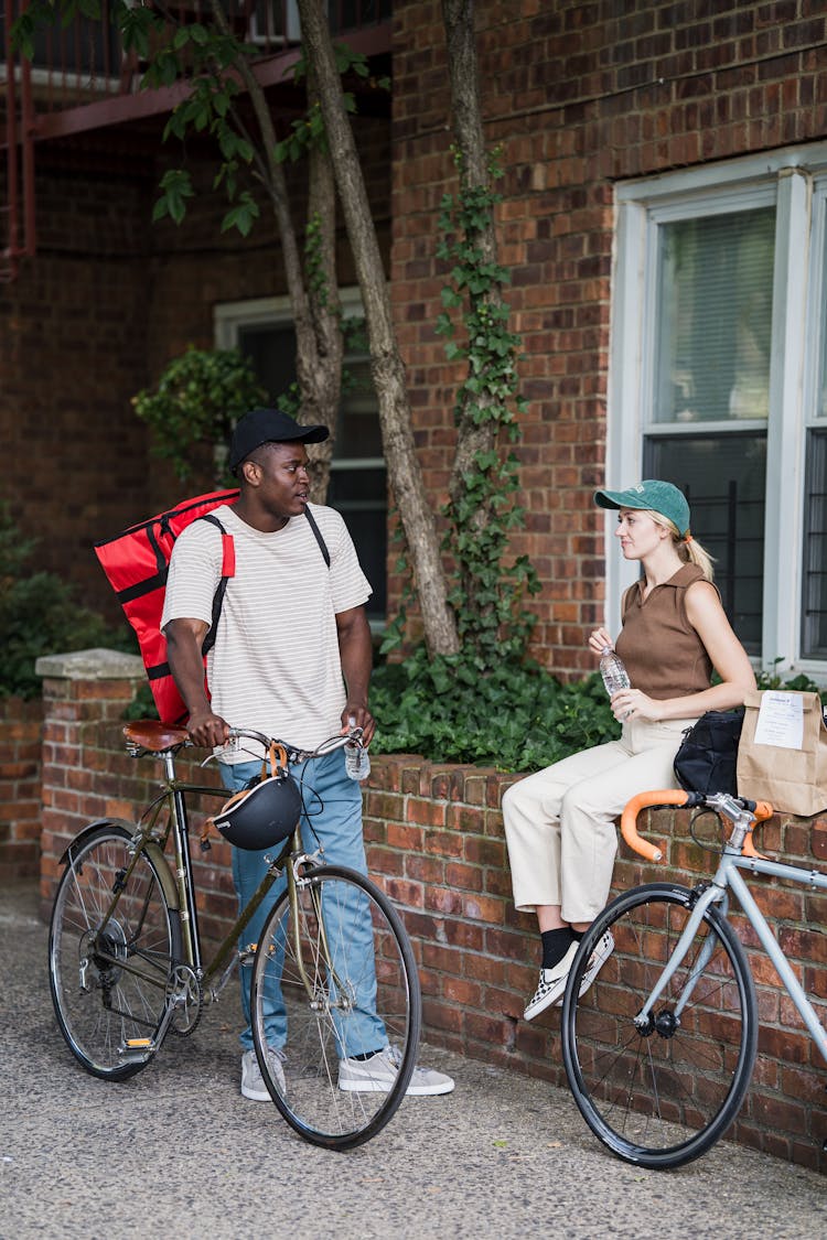 Colleagues From Food Delivery Service Resting And Talking In Street