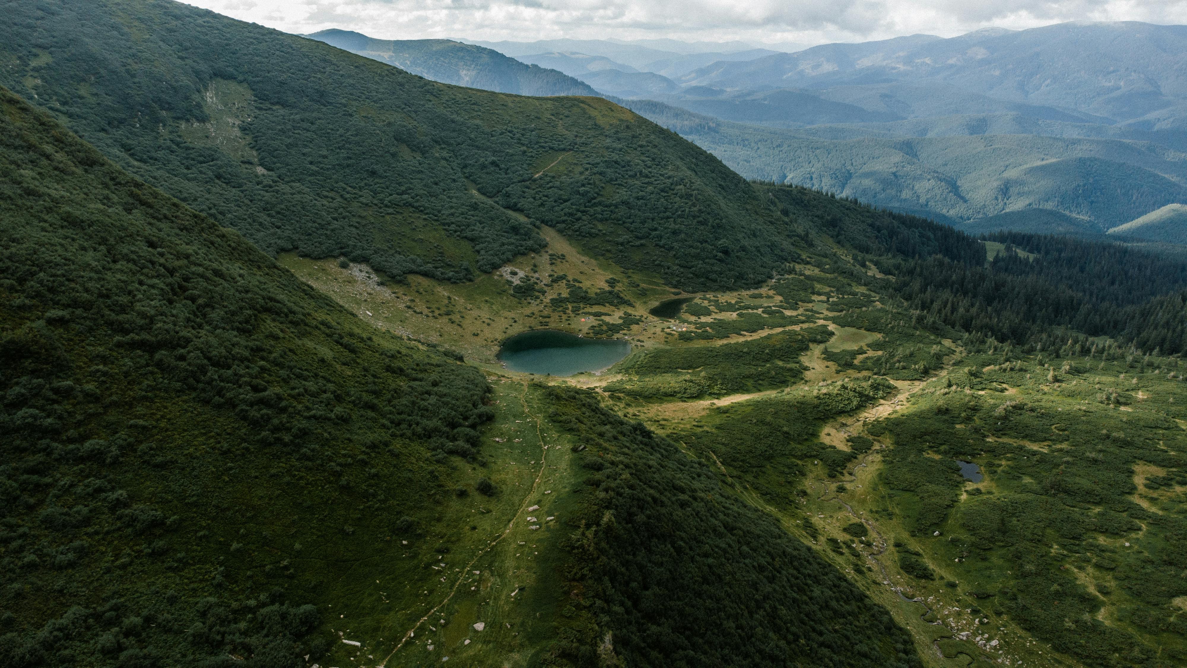 A breathtaking aerial view of the lush Carpathian Mountains in Ukraine with a serene lake.