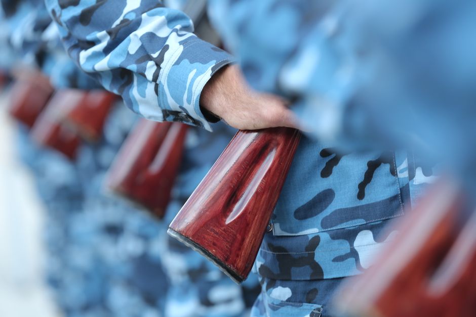 Close-up of soldiers in blue camouflage holding rifles in formation.