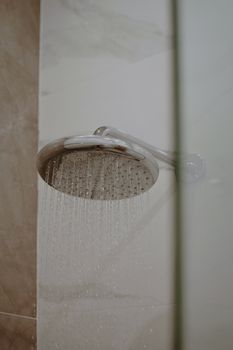 Close-up of a modern showerhead with water flowing indoors. Ideal for lifestyle and home decor use.