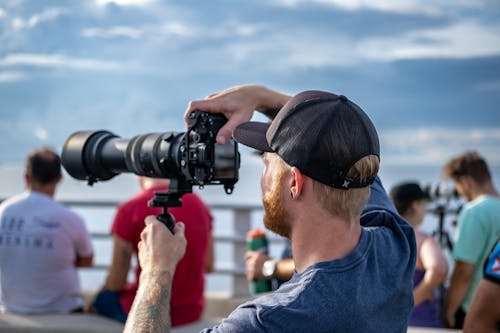 Man in Blue Shirt Taking Photo with a Camera