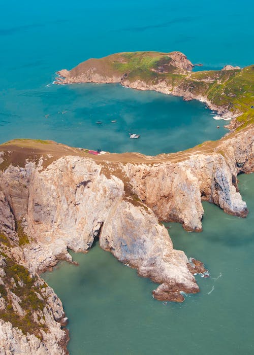 Brown and Green Rock Formation Beside Blue Sea