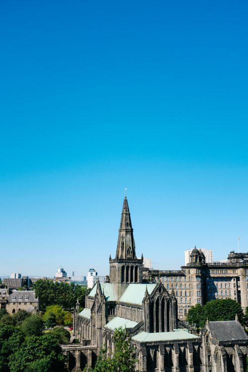 Free Aerial shot of Glasgow Cathedral under a clear blue sky, showcasing Gothic architecture. Stock Photo