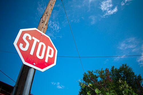 Free Vibrant stop sign against a clear blue sky with trees in Greece. Stock Photo