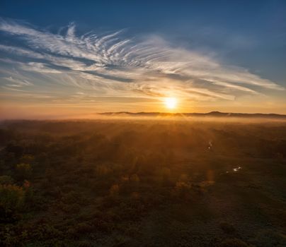 A breathtaking aerial landscape of Trevino, WI during golden hour, showcasing a serene sunset over a lush forest.