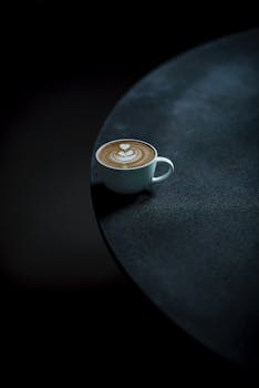 Elegant latte art in a coffee cup against a dark, minimalist background.