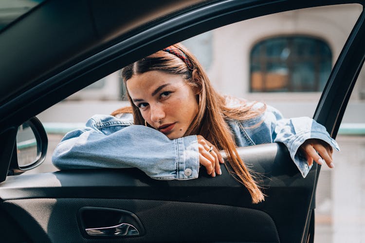 Woman In Denim Jacket Leaning On Car Door