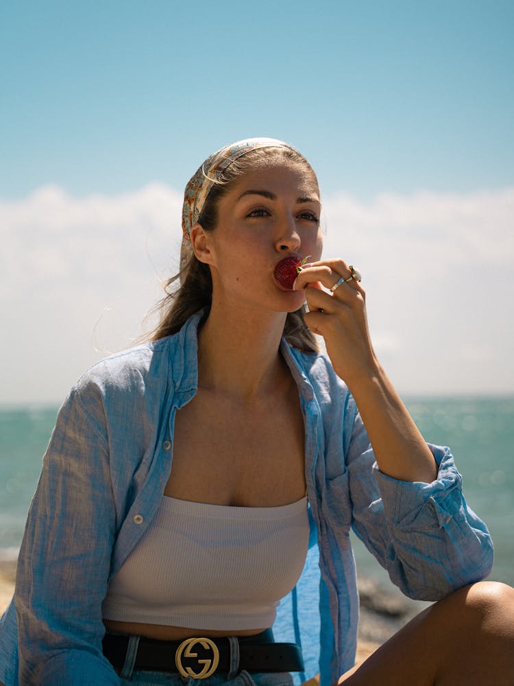 Woman In Button Down Shirt Eating A Fruit