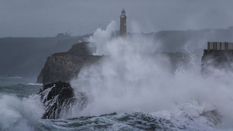 Crashing Waves Near A Lighthouse Tower